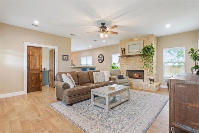 living room with visible vents, a fireplace, light wood-style floors, baseboards, and ceiling fan