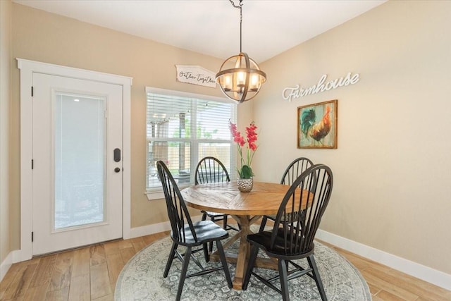 dining space featuring light wood-style floors, baseboards, and a notable chandelier