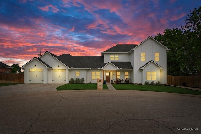 view of front of property featuring concrete driveway, an attached garage, fence, and a front lawn