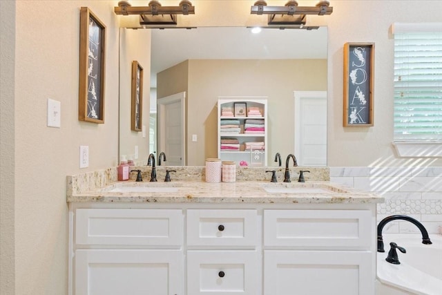 bathroom featuring double vanity, a sink, and a bath
