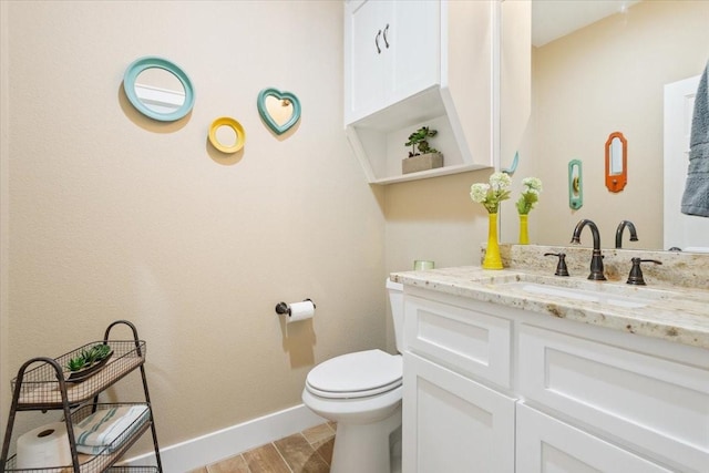bathroom featuring toilet, baseboards, wood finished floors, and vanity