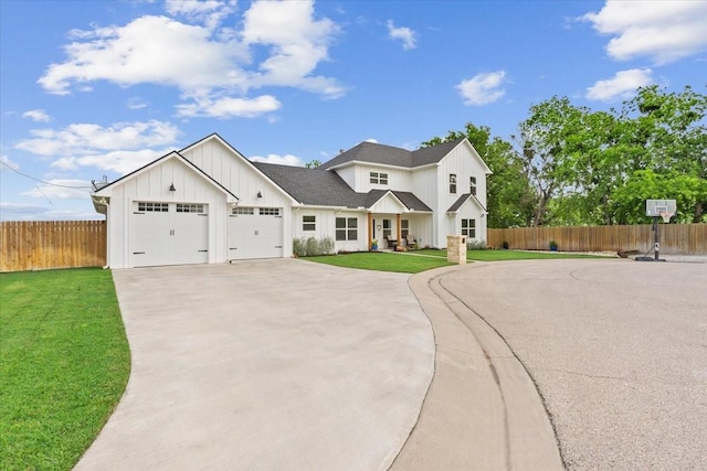 modern farmhouse featuring board and batten siding, a front yard, a garage, fence, and concrete driveway