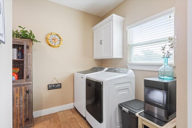 laundry area with light wood-style floors, baseboards, cabinet space, and washer and dryer