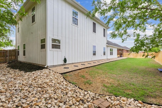 rear view of house featuring board and batten siding, a yard, and a fenced backyard