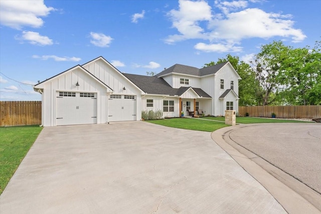 modern farmhouse style home with fence, a front lawn, a garage, board and batten siding, and driveway