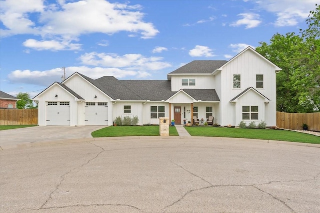 modern farmhouse style home with fence, a front yard, board and batten siding, an attached garage, and driveway