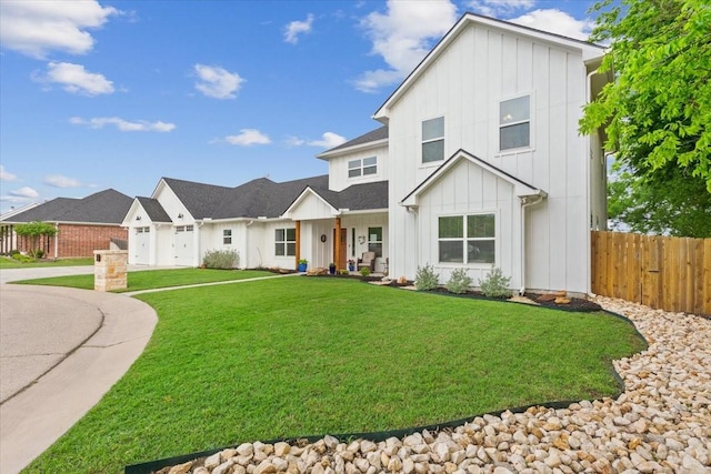 modern farmhouse featuring board and batten siding, driveway, a front yard, fence, and an attached garage