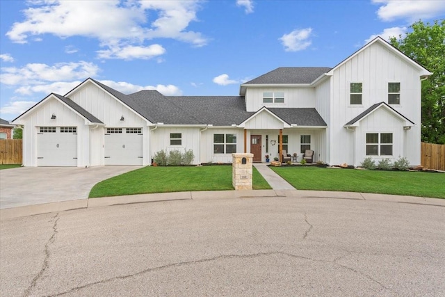 modern farmhouse style home with fence, board and batten siding, driveway, and a front lawn