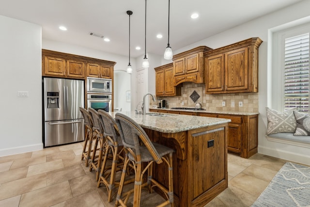 kitchen with tasteful backsplash, a sink, brown cabinetry, stainless steel appliances, and visible vents