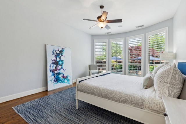 bedroom with wood finished floors, visible vents, baseboards, and ceiling fan