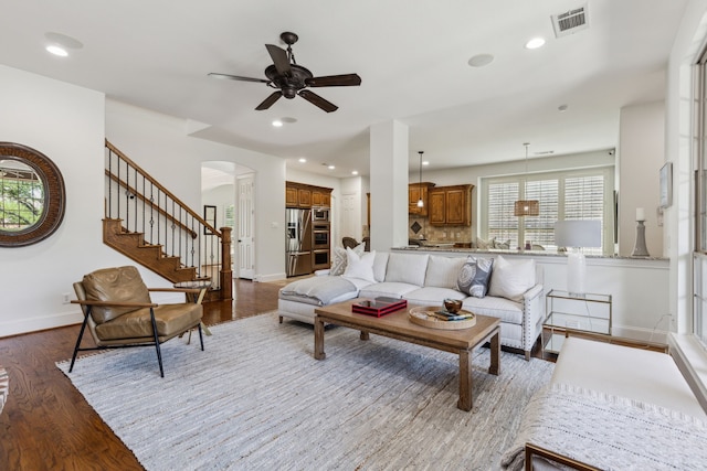 living area with wood finished floors, visible vents, arched walkways, baseboards, and ceiling fan