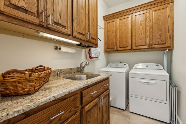 washroom featuring washer and clothes dryer, light tile patterned flooring, a sink, and cabinet space