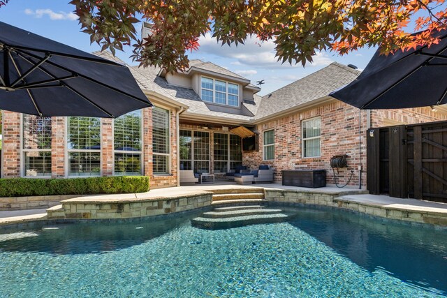 rear view of house featuring an outdoor pool, a shingled roof, fence, a patio, and brick siding