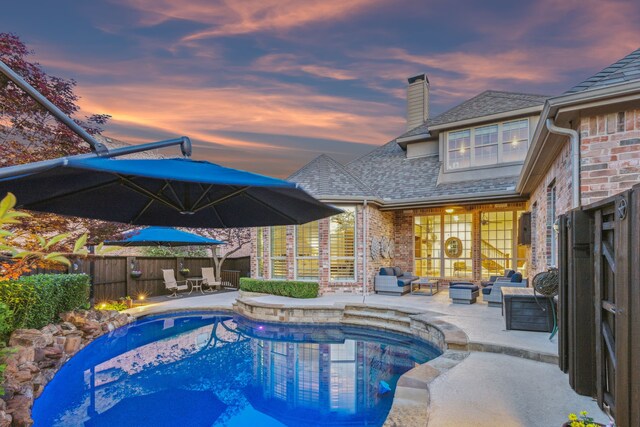 pool at dusk with a fenced backyard, outdoor lounge area, a patio area, and a fenced in pool