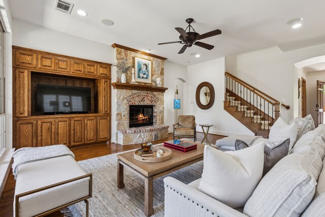 living area with arched walkways, visible vents, recessed lighting, a ceiling fan, and a stone fireplace