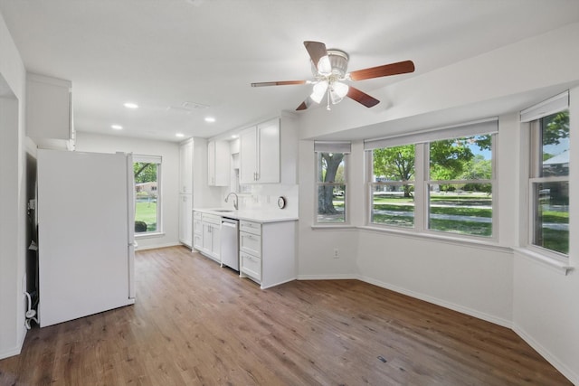 kitchen with light countertops, freestanding refrigerator, dishwasher, and baseboards