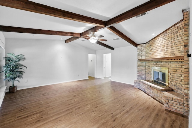 unfurnished living room with ceiling fan, a fireplace, visible vents, wood finished floors, and vaulted ceiling with beams