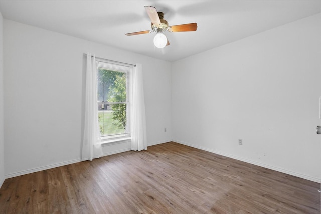 unfurnished room with ceiling fan, wood finished floors, and baseboards