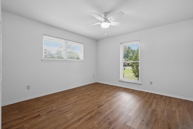 empty room with plenty of natural light, baseboards, a ceiling fan, and wood finished floors