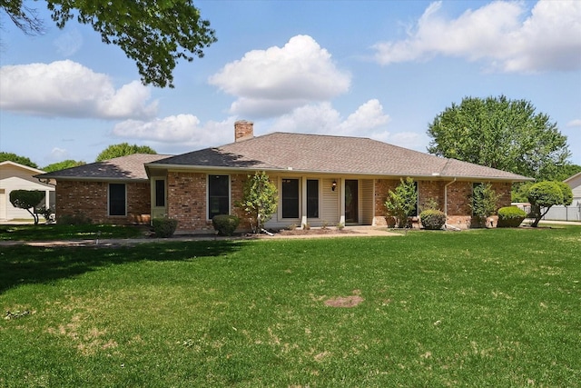 single story home with brick siding, a front yard, and a chimney