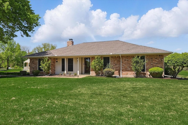 single story home with roof with shingles, a chimney, a front yard, and brick siding
