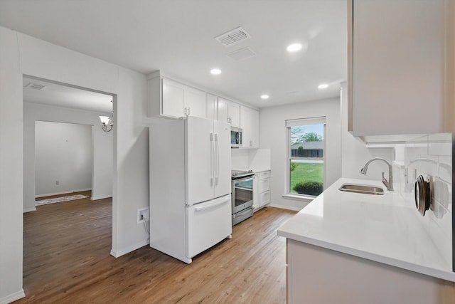 kitchen with light wood-type flooring, light countertops, visible vents, appliances with stainless steel finishes, and a sink