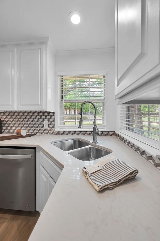 kitchen featuring dishwasher, white cabinets, a sink, and plenty of natural light