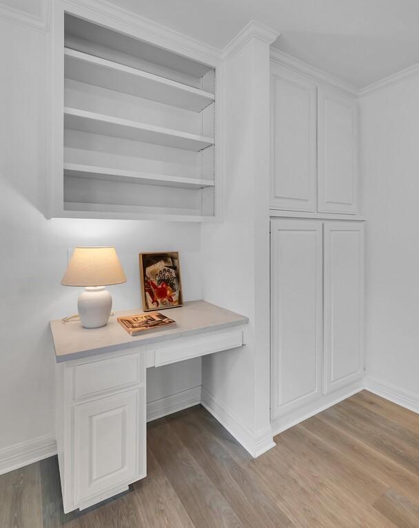 interior space featuring built in study area, wood finished floors, and baseboards