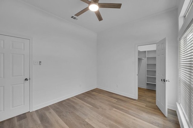 unfurnished bedroom with a spacious closet, visible vents, a closet, baseboards, and light wood-style flooring