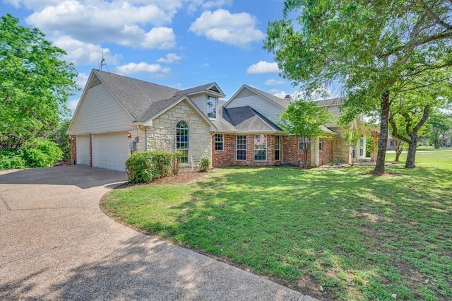 traditional-style home featuring a shingled roof, a front lawn, an attached garage, driveway, and stone siding
