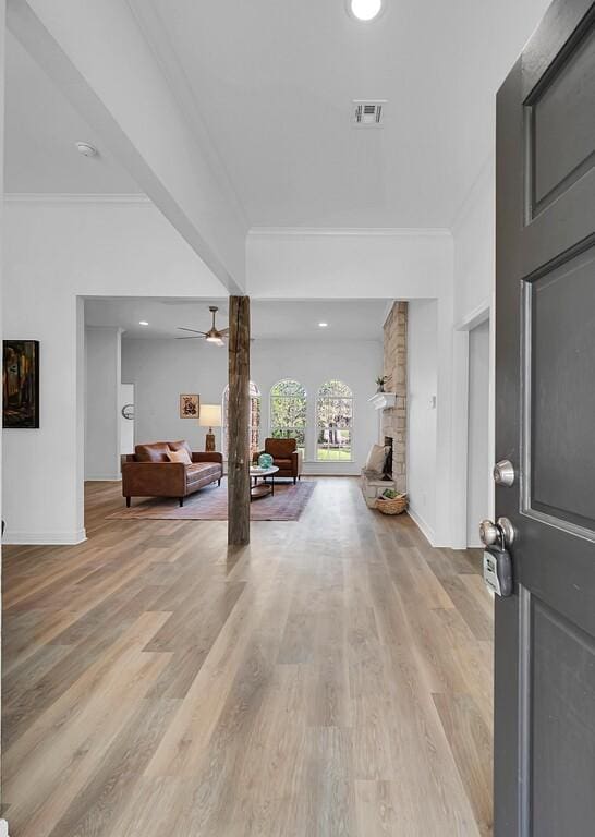 entryway featuring light wood-style floors, visible vents, crown molding, and a ceiling fan