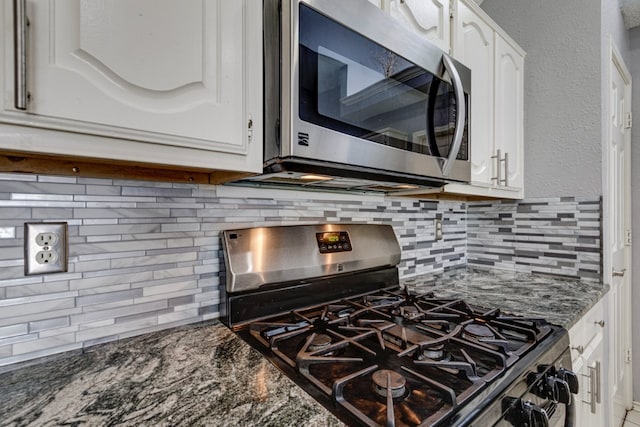 kitchen with dark stone counters, white cabinets, stainless steel appliances, and decorative backsplash