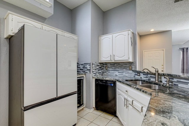 kitchen featuring black dishwasher, dark stone countertops, freestanding refrigerator, and white cabinetry