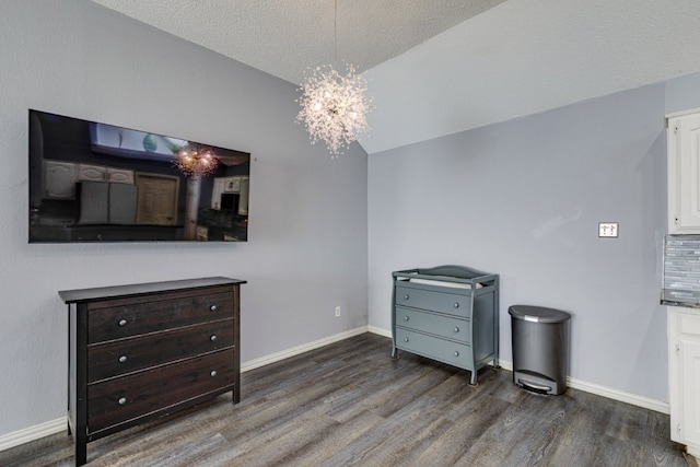 bedroom with wood finished floors, an inviting chandelier, baseboards, a textured ceiling, and lofted ceiling