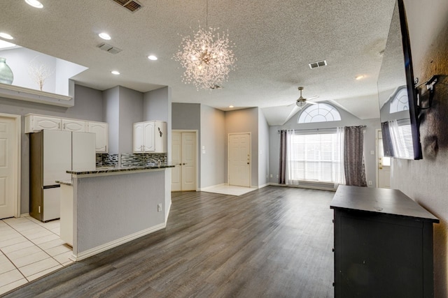 kitchen with a textured ceiling, visible vents, freestanding refrigerator, open floor plan, and ceiling fan with notable chandelier