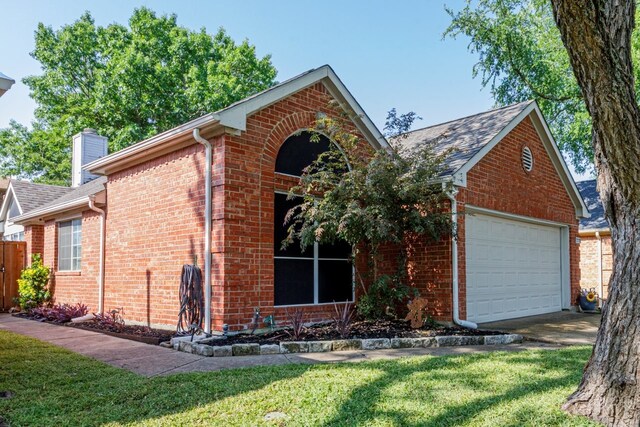 ranch-style home with a front yard, a garage, brick siding, driveway, and a chimney