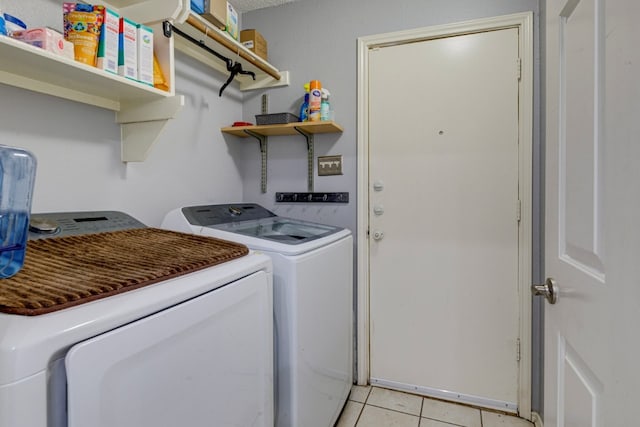 clothes washing area with light tile patterned floors, independent washer and dryer, and laundry area