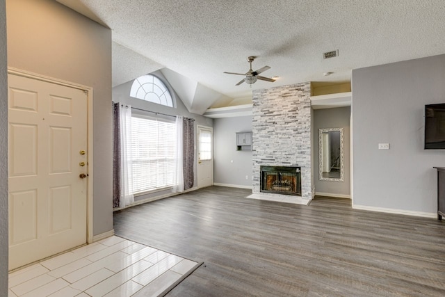 unfurnished living room featuring ceiling fan, a multi sided fireplace, visible vents, vaulted ceiling, and wood finished floors