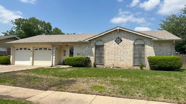 ranch-style home with concrete driveway, brick siding, an attached garage, and a front yard