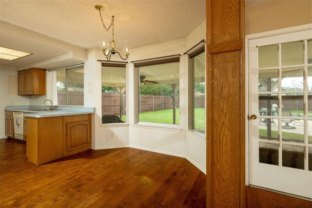 kitchen featuring dark wood-style flooring, a sink, baseboards, light countertops, and a chandelier