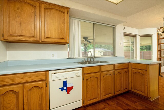 kitchen featuring light countertops, white dishwasher, a sink, and dark wood-type flooring