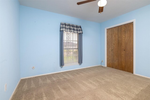 unfurnished bedroom featuring a closet, baseboards, ceiling fan, and carpet flooring