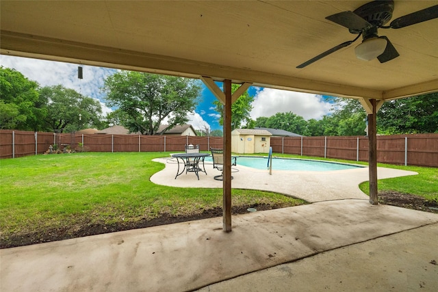 view of swimming pool featuring a patio, a fenced backyard, a ceiling fan, and a lawn