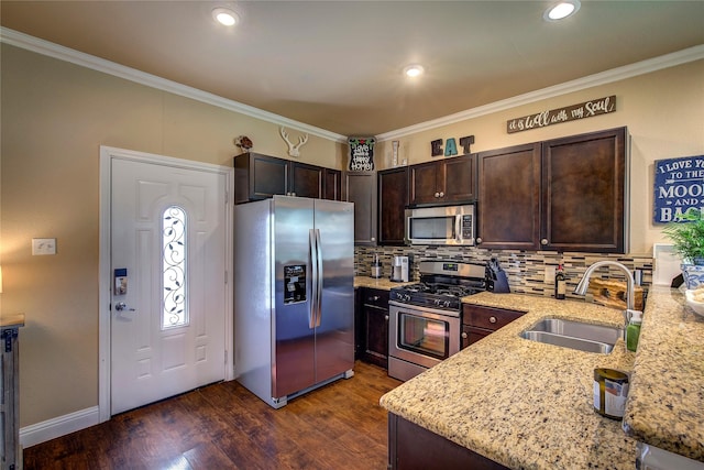 kitchen featuring dark brown cabinetry, appliances with stainless steel finishes, light stone counters, a sink, and backsplash