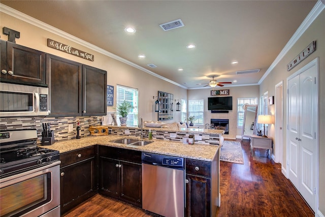 kitchen featuring visible vents, a sink, appliances with stainless steel finishes, a peninsula, and dark wood-style floors