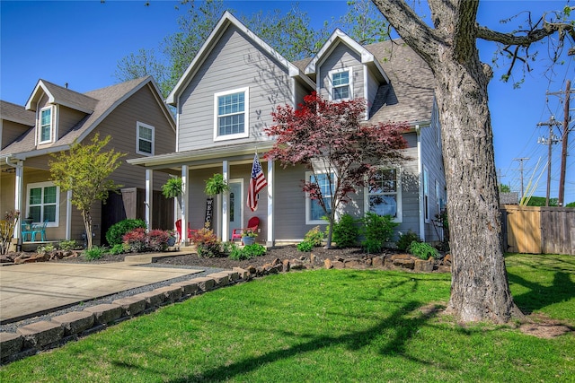 view of front of house with a front yard, a porch, and fence