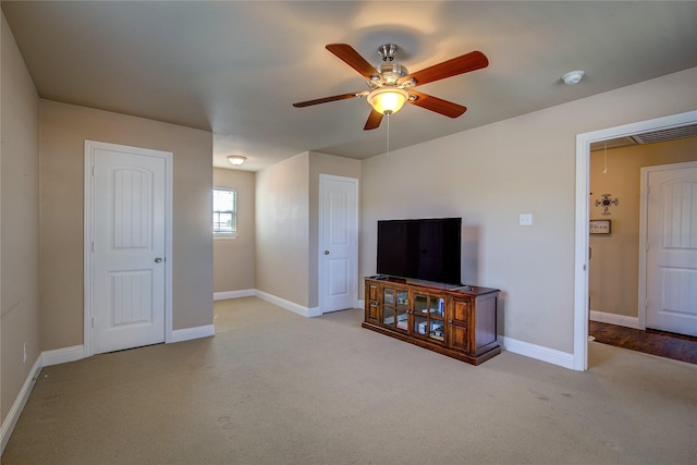 unfurnished living room with baseboards, attic access, a ceiling fan, and carpet floors