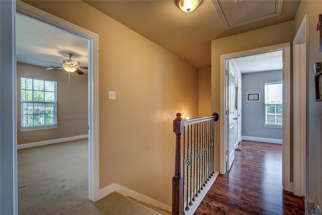 hallway featuring dark wood-style flooring, baseboards, and an upstairs landing