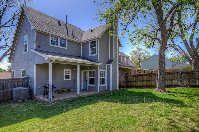 back of house with a patio, roof with shingles, a fenced backyard, and a lawn
