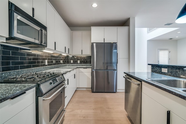 3251 Cambrick St Unit 13, Dallas, TX 75204 - kitchen featuring stainless steel appliances, backsplash, a sink, light wood-type flooring, and dark stone counters